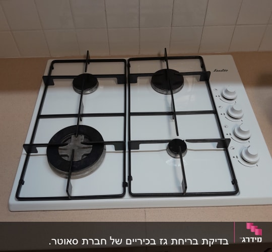 כיריים גז לבנות עם ארבעה מבערים וכפתורי שליטה